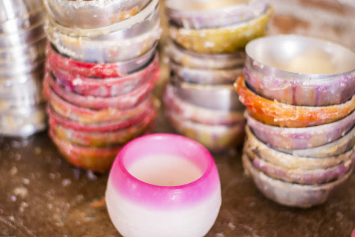 Moldes circulares con parafina y un cuenco solor rosa sobre mesa de taller artesanal de cuencos porta velas