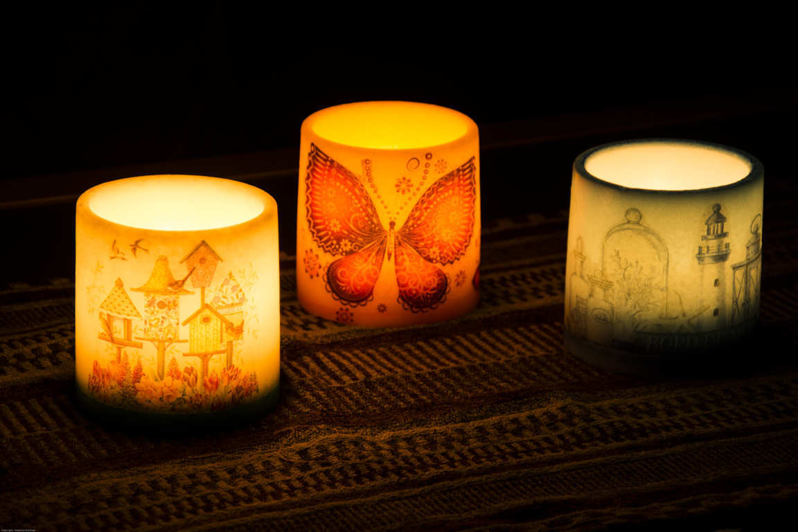 Tres cuencos con dibujos iluminados con una vela interior en ambiente oscuro
