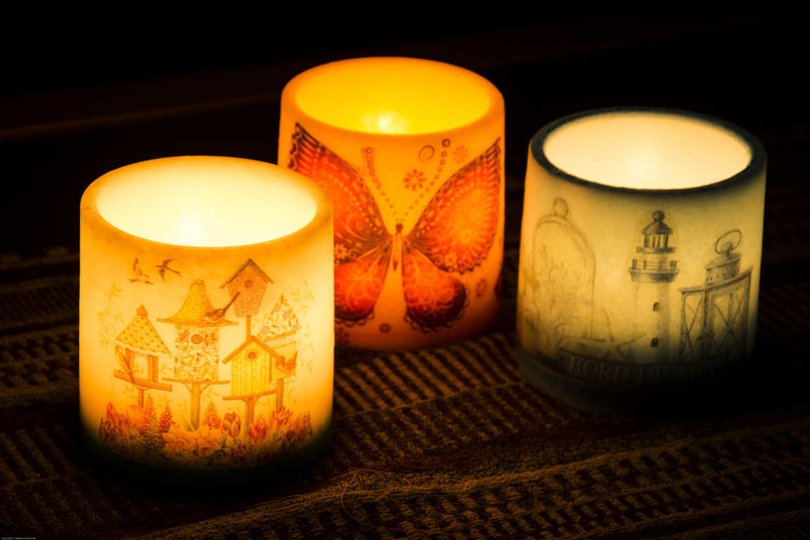 Tres cuencos con dibujos iluminados con una vela interior en ambiente oscuro